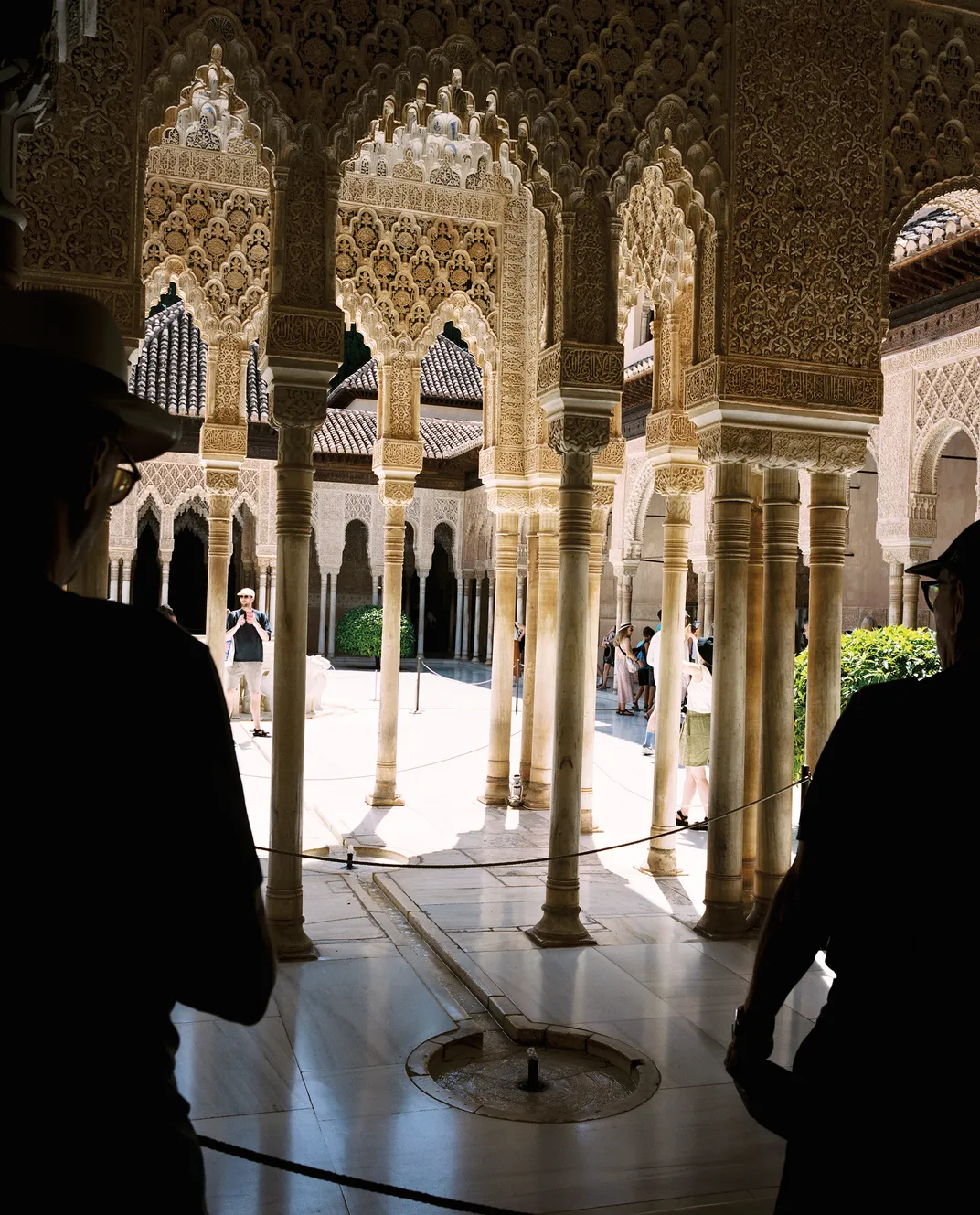 a palace courtyard with tourist amongst columns