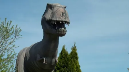 A Tyrannosaurus stands over the remains of an abandoned mini-golf course.