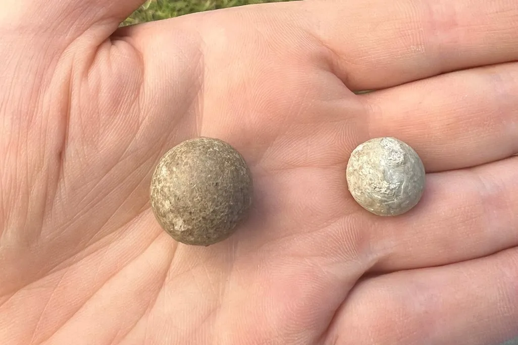 A person's hand holding two small spheres