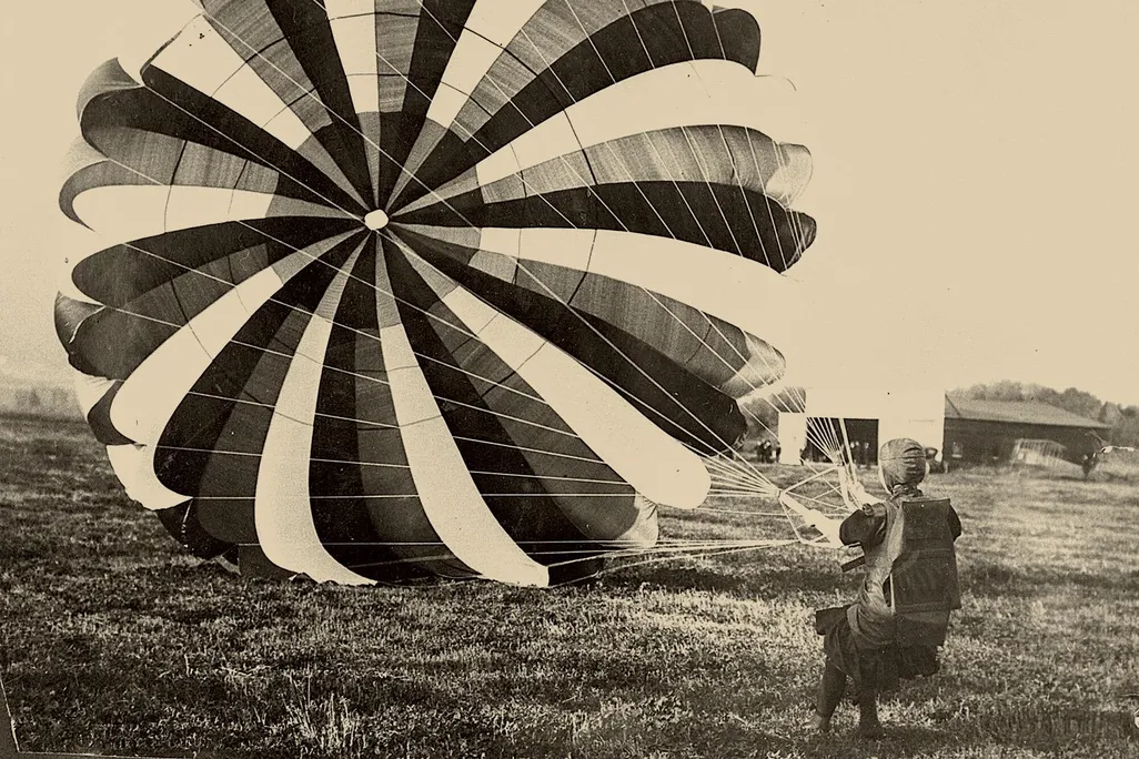 A woman holding the strings to a parachute canopy, having just landed
