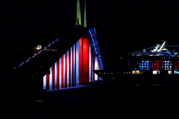 Cruise ship returning to port about to sail under illuminated Skyway Bridge with Patriotic light theme thumbnail