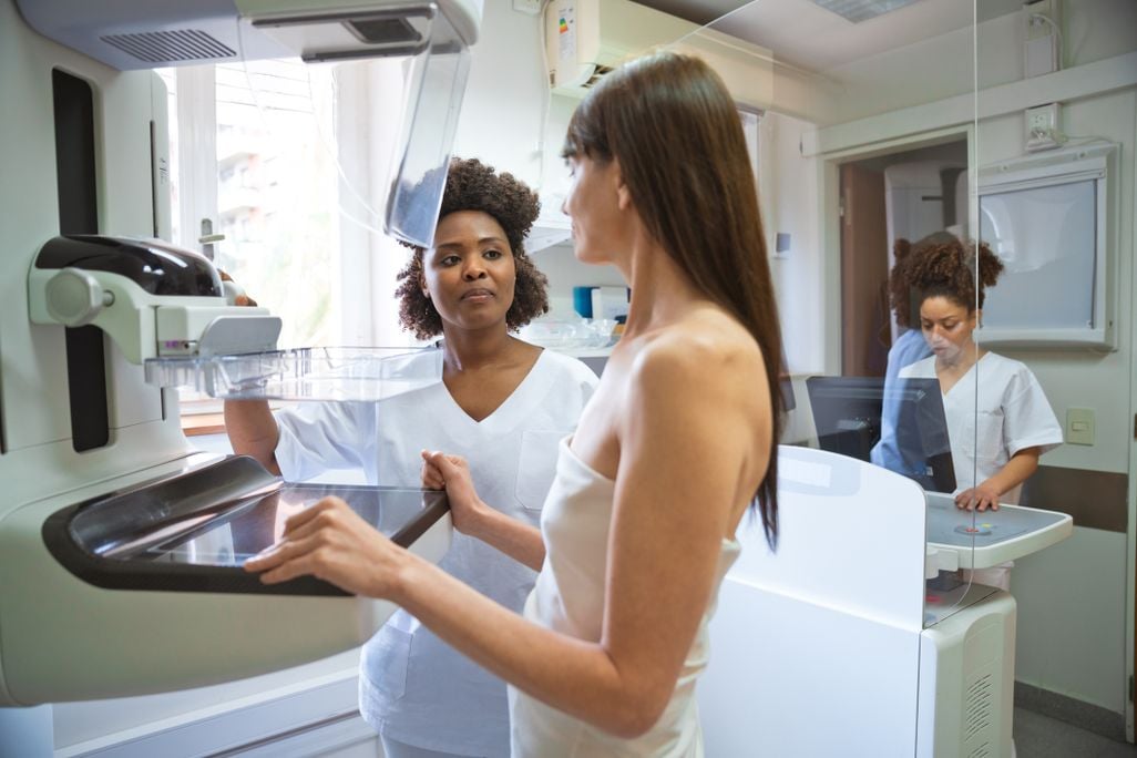a nurse explains how to use a mammography machine to a patient