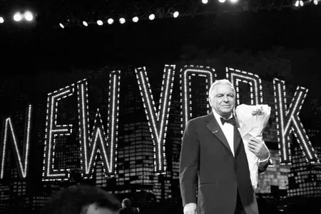 Frank Sinatra clutches a bouquet of flowers handed to him by an admirer following his show at Radio City Music Hall in New York City, 1990