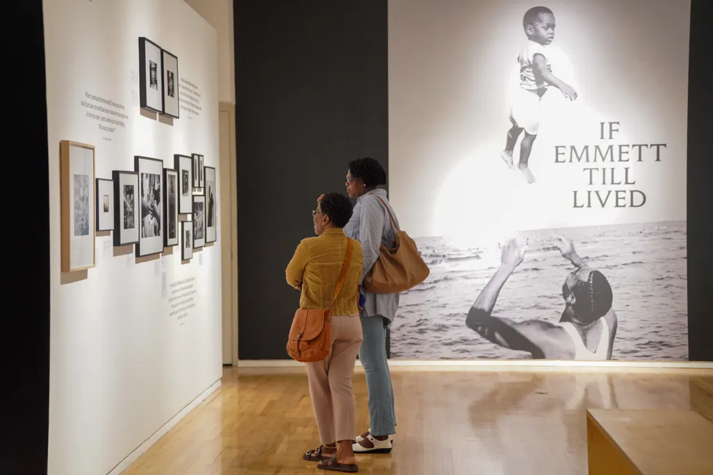 Two women looking at photographs on a wall