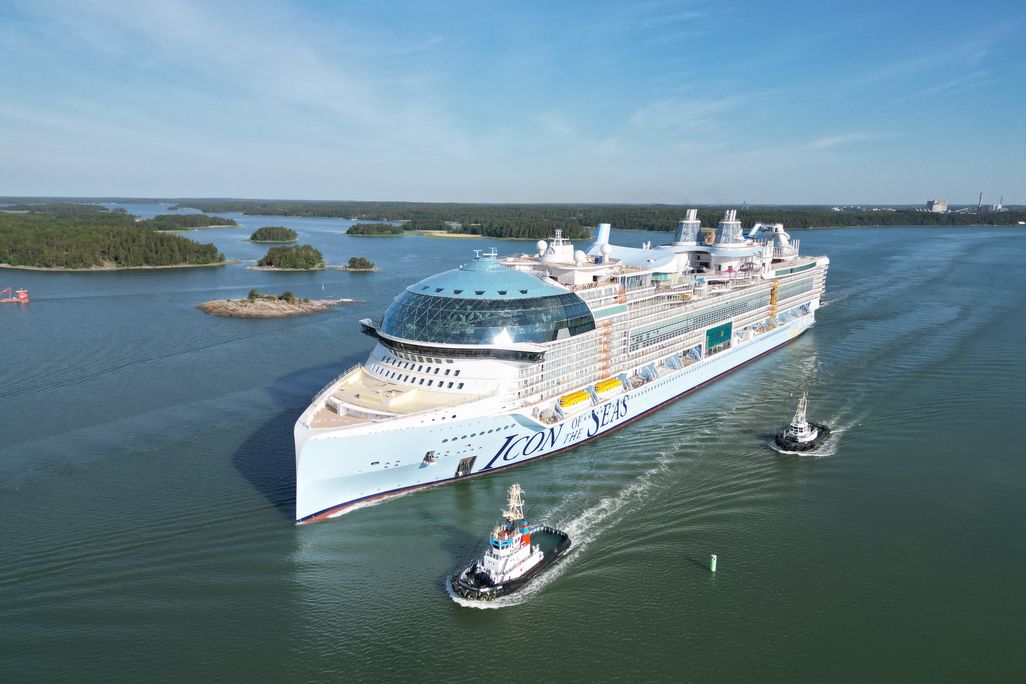 Large cruise ship with tug boats in the water nearby