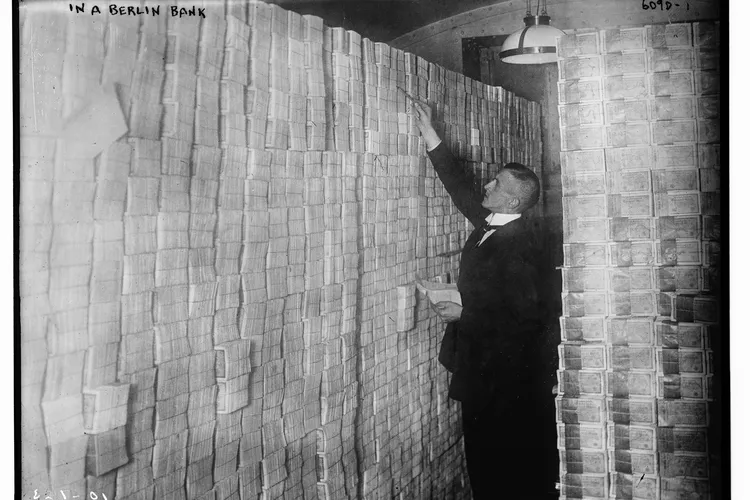 A man standing next to stacks of German marks at a Berlin bank