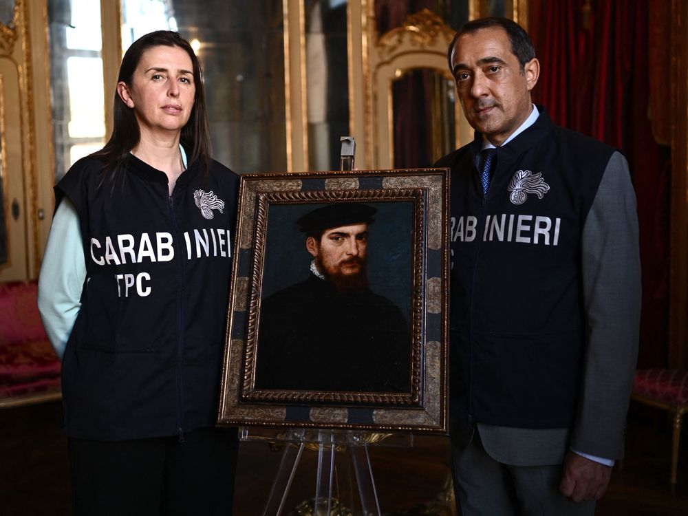 Members of the Carabinieri Police Cultural Heritage Protection Unit pose with a painting