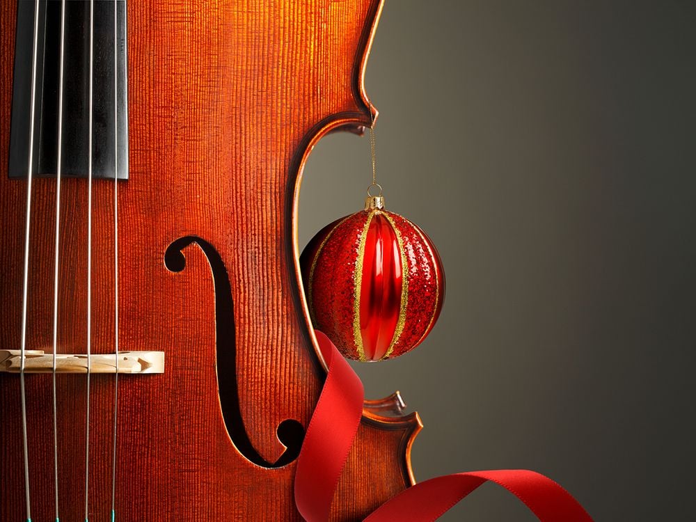 A portion of a violin is shown accented with red ribbon and an ornament
