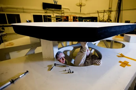 Betsy Congdon, lead engineer for Parker Solar Probe’s heat shield, looks on as technician Tony Ahan attaches the interface plates that will allow the heat shield above them to eventually be installed onto the spacecraft. 