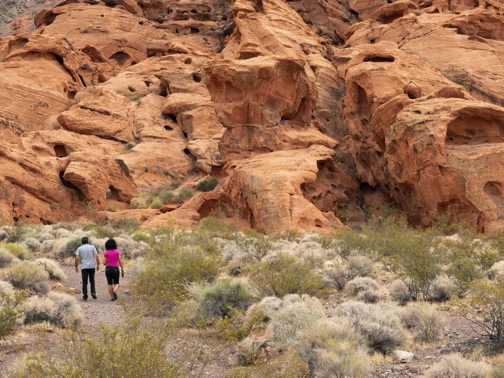 Two people hiking among red sandstone formations