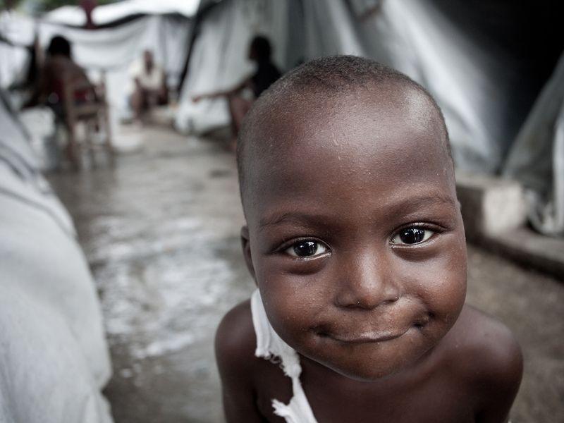 A young boy in a tent city in Port-au-Prince Haiti smiles for the ...