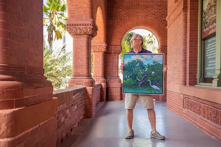 A man holding a painting featuring Key West's beautiful wildlife