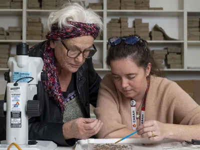 Sue O&#39;Connor (left) and Shimona Kealy (right) study some of the artifacts found in Timor-Leste, which offer clues that early humans took a more northern path from Southeast Asia to Australia tens of thousands of years ago.