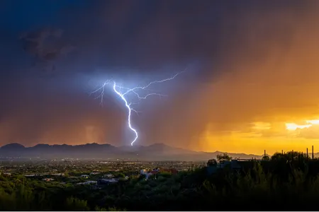 Lightning from a summer monsoonal thunderstorm strikes in Tucson just as the sun sets.&nbsp;