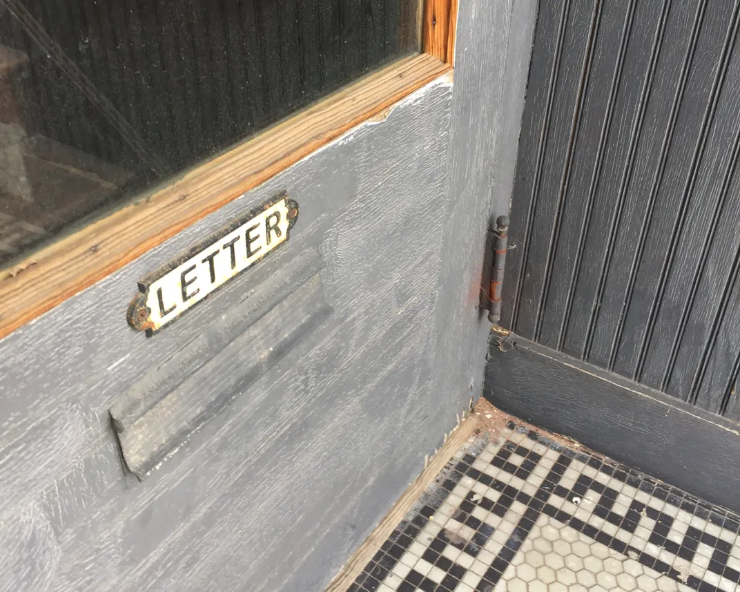 A mail slot on a gray door