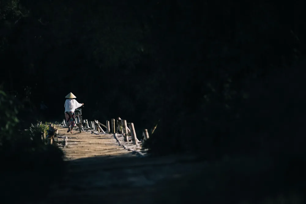 Locals cross a small wooden foot bridge