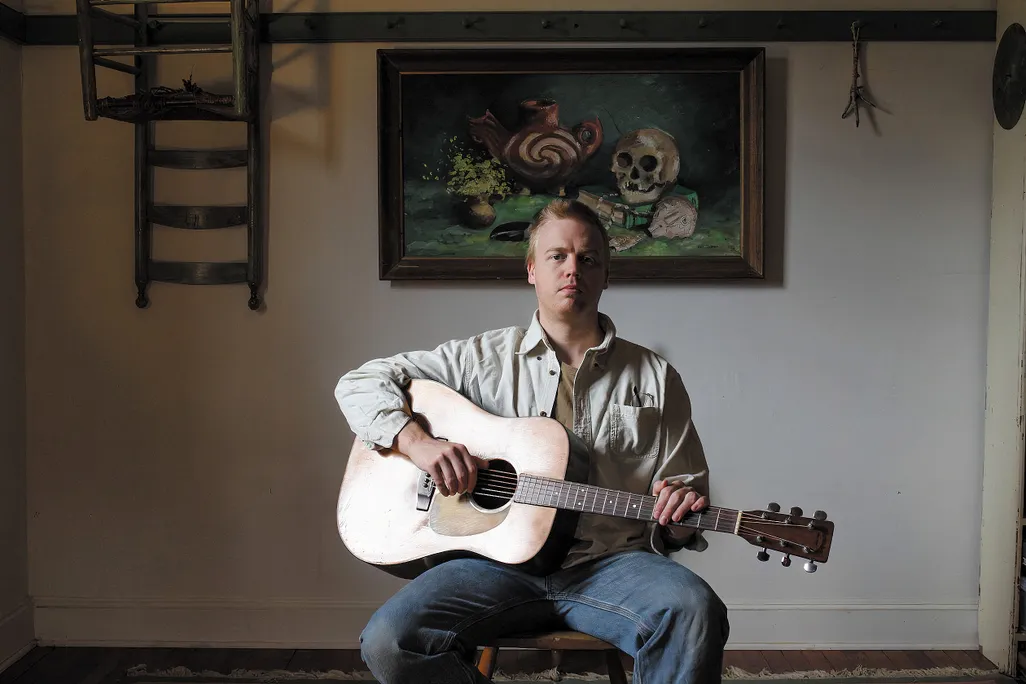 a man sits with his guitar
