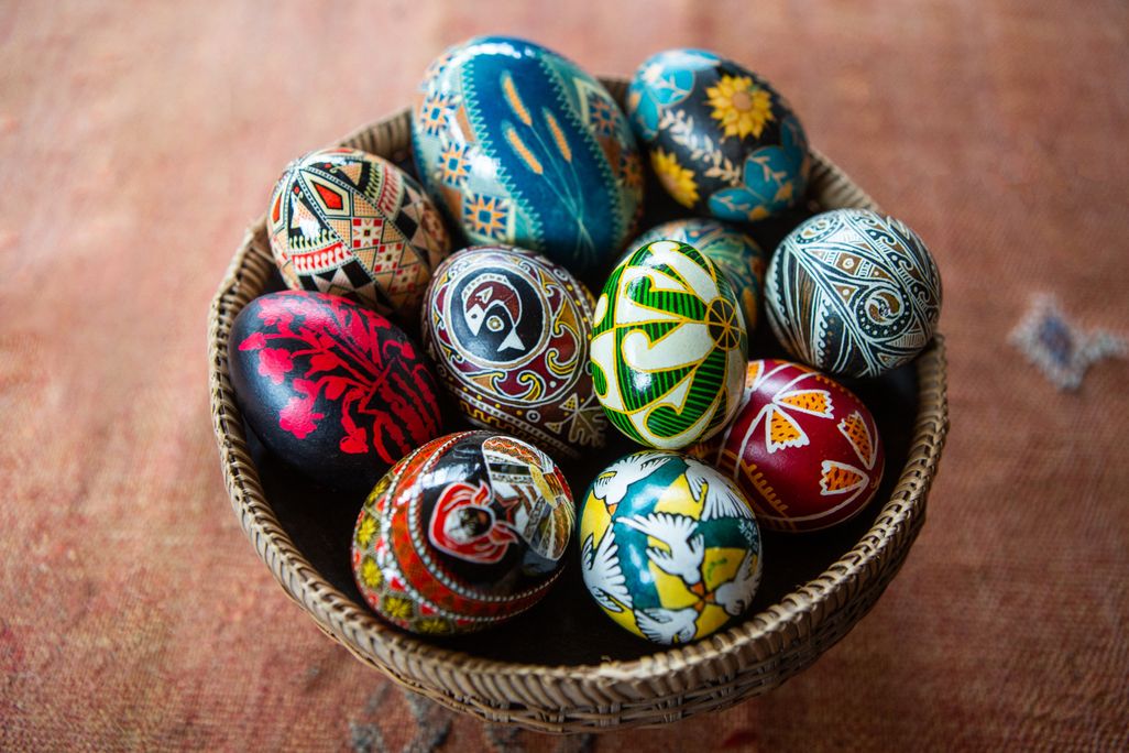A bowl filled with intricately decorated, multicolored eggs