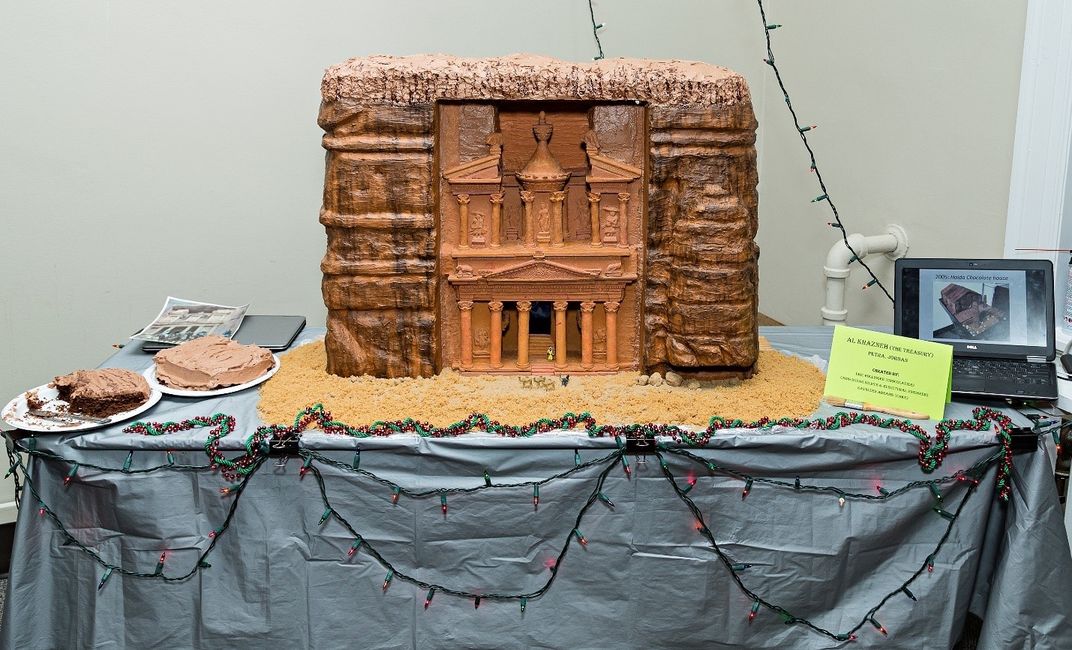 Orange cake recreation of Petra on a rectangular table with a blue-gray tablecloth. 