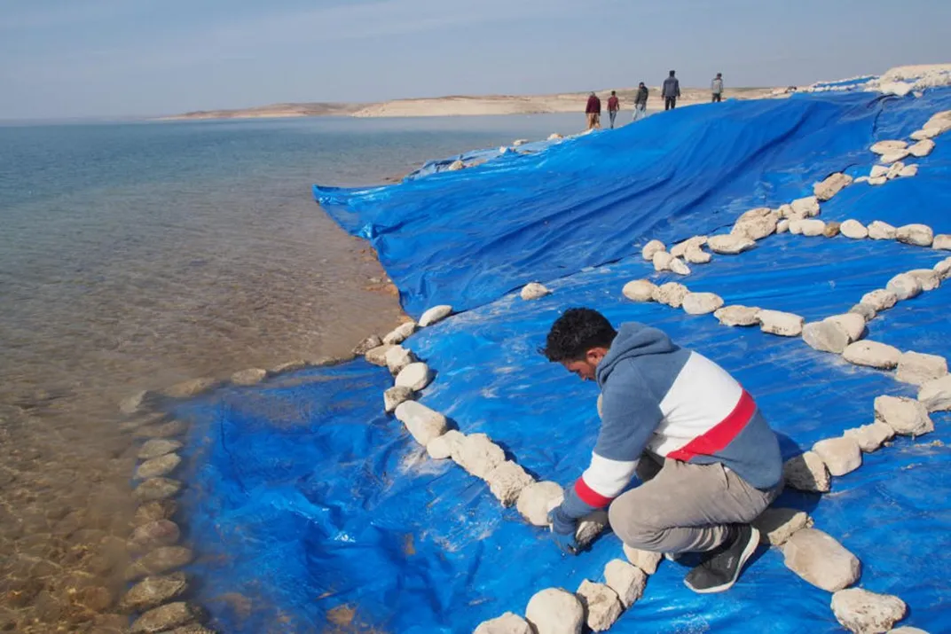 A man covering an area with tarps and rocks