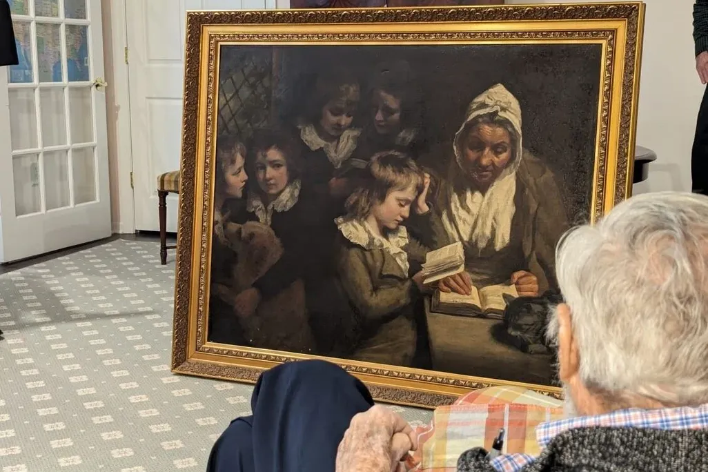 Large painting in a frame in front of a man with white hair