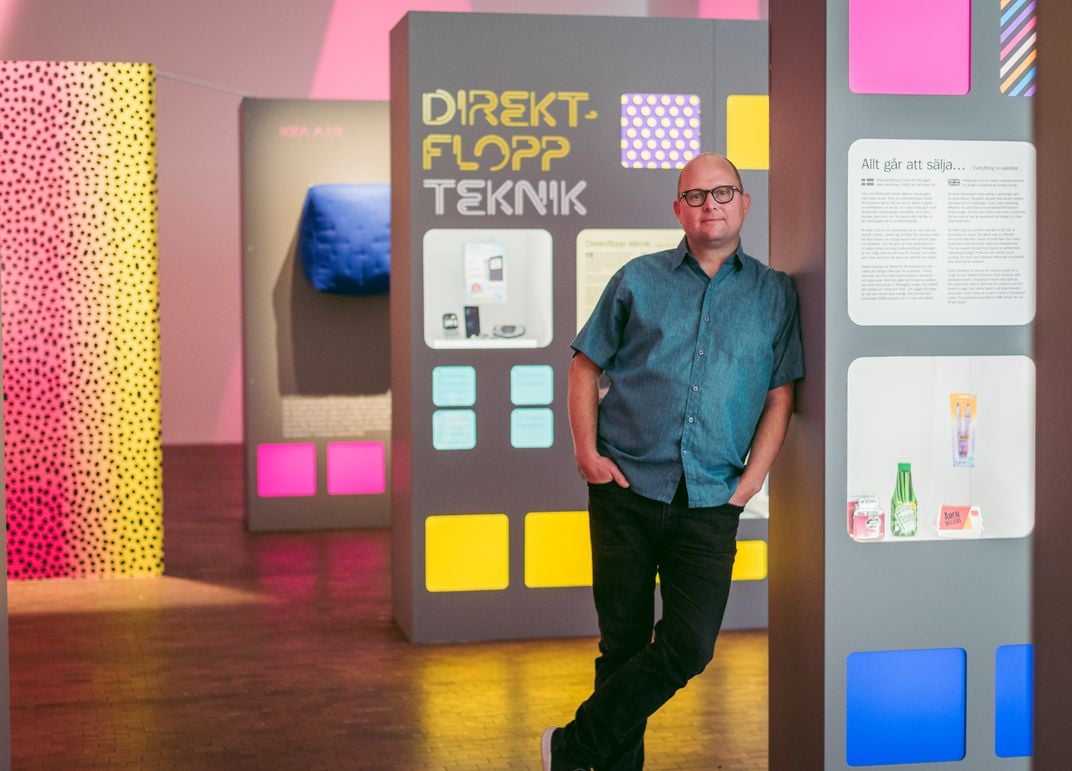 Man leaning against colorful exhibit display