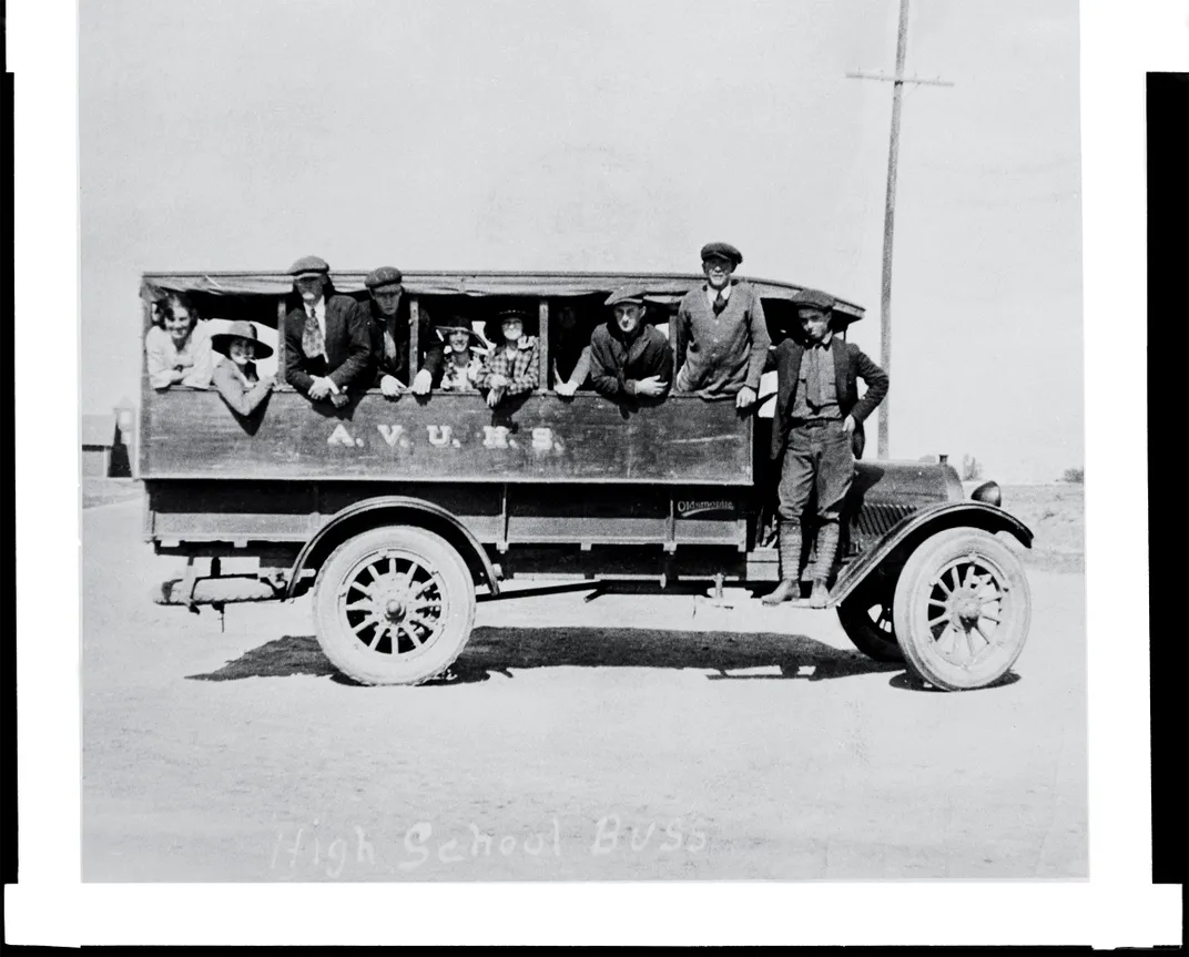 a black and white photography from 1909 of kids on a school bus