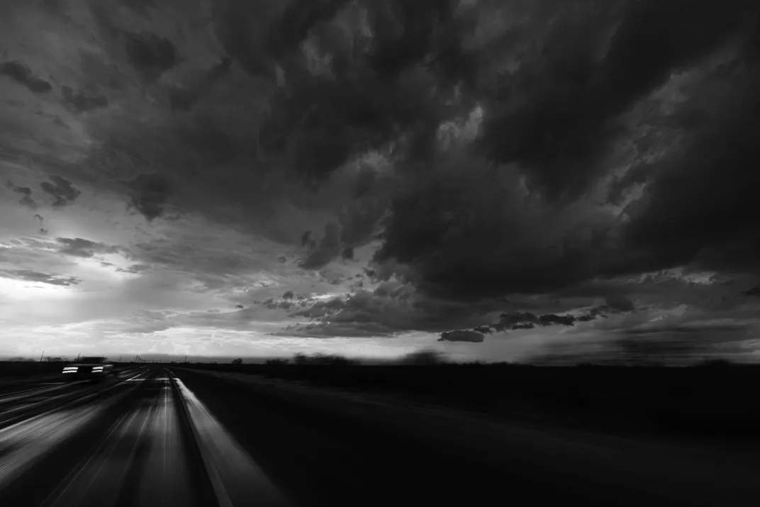 3 - Ominous clouds loom above a road, casting a heavy shadow that darkens the landscape.