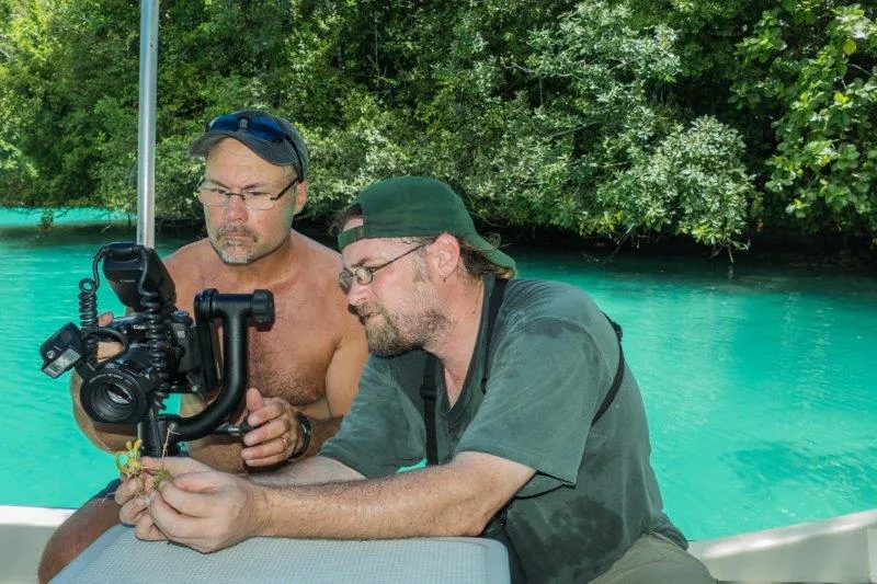 Two men looking through camera on water