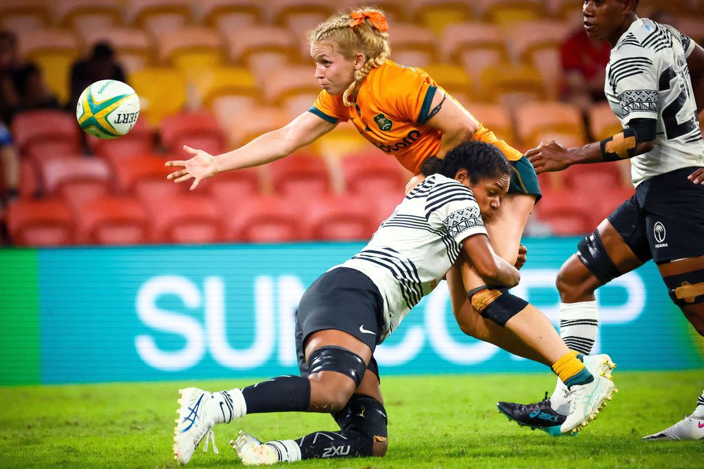 A woman gets tackled while playing rugby