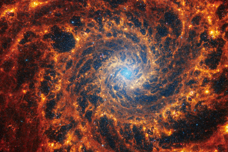 Spiral galaxy NGC 628, located 32 million light-years away in the constellation Pisces, as captured by the James Webb Space Telescope in near- and mid-infrared light. The red and orange spirals represent gas, while the small blue dots represent stars.