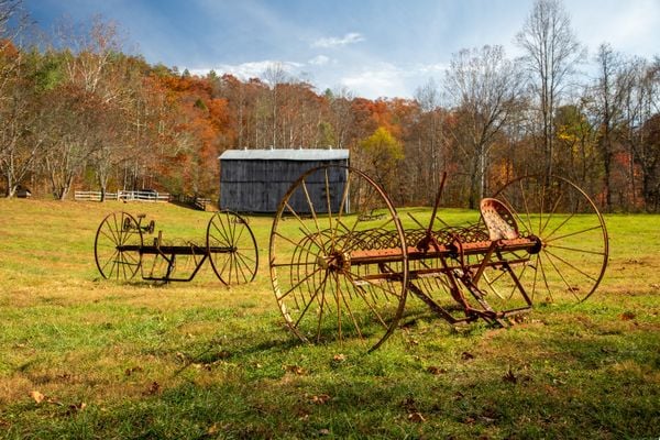 Agricultural farm equipment in field in front of old barn thumbnail