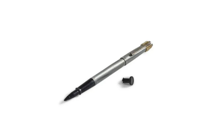 A pen and a little piece of black plastic against a white backdrop