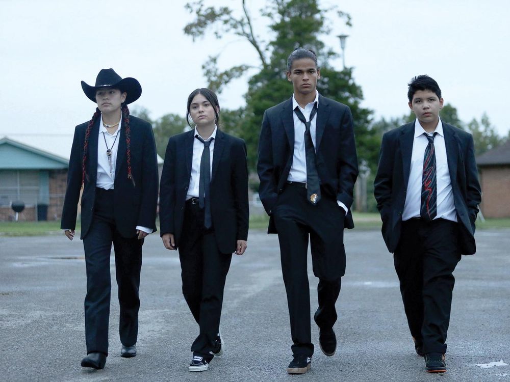 four Native American teenagers in black suits walking