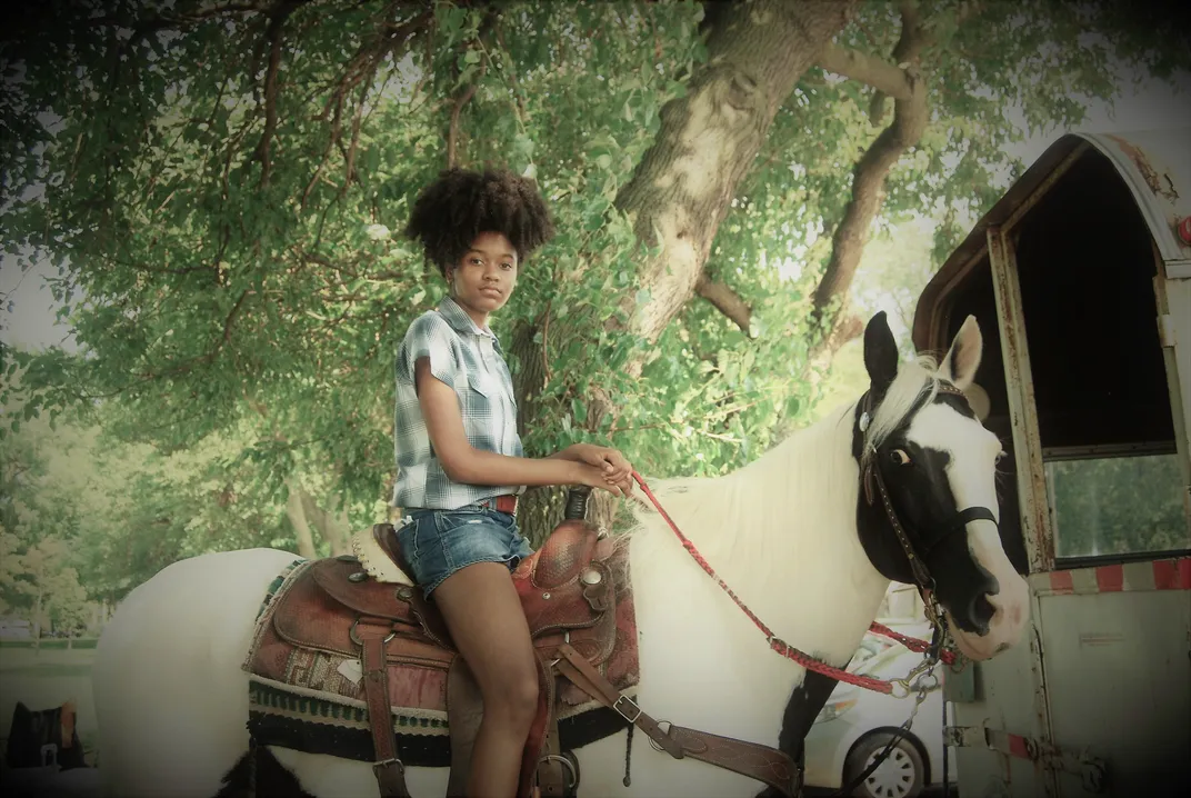 A young rider saddles up on a white steed