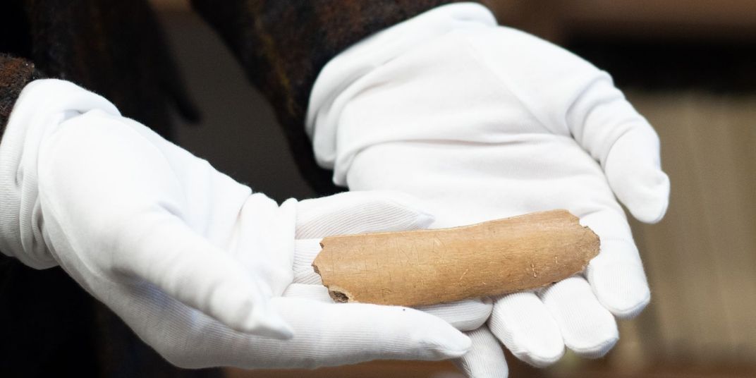 Researcher holds cow bone inscribed with Germanic runes