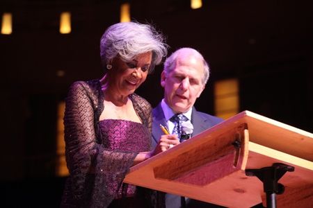 Nancy Wilson signs the deed of gift, donating two of her gowns to the American History Museum, alongside museum director Brent Glass, at the Music Center at Strathmore.