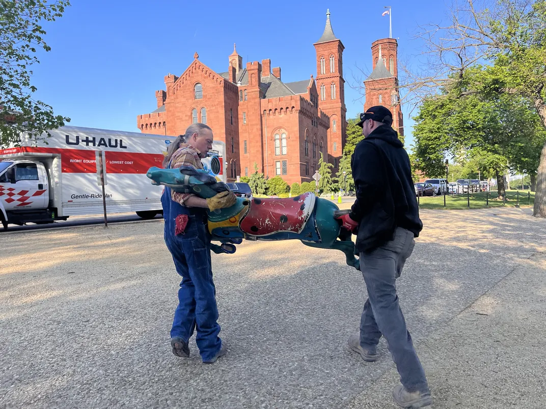 Workers transport a carousel horse to a truck.