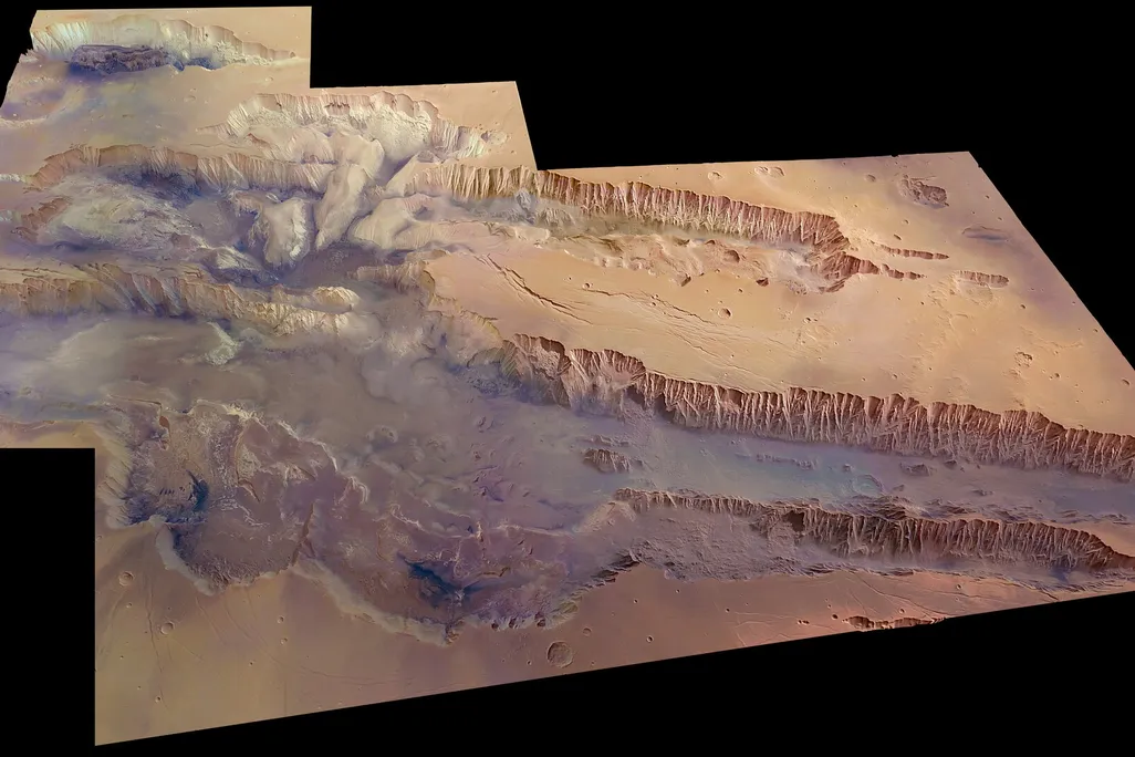 An image of the Valles Marineris on planet Mars. The region is as large as the United States and the biggest canyon in the Solar System. The region looks red and arid.