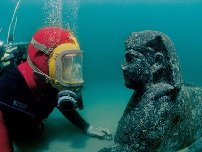 Archaeologist eye to eye to with a sphinx underwater, Eastern Harbor, Alexandria, Egypt, 1st century BC; granodiorite; 27 9/16 x 59 1/16 inches; National Museum of Alexandria (SCA 450); IEASM Excavations; Photos: Jèrôme Delafosse © Franck Goddio / Hilti Foundation.
