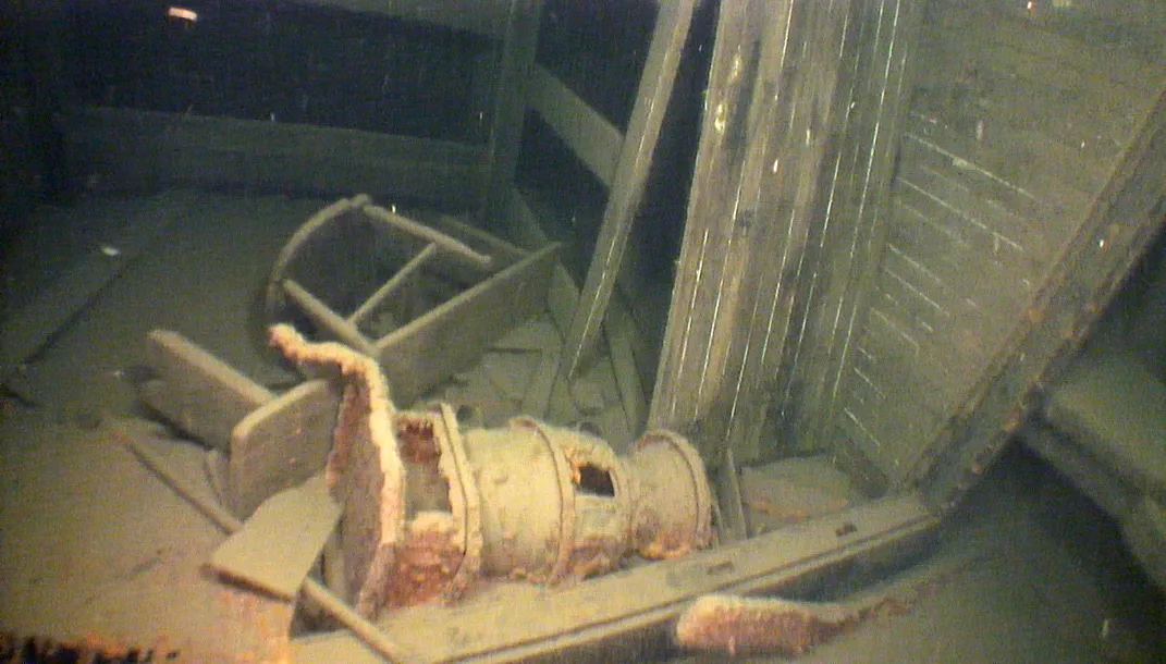 A view of cabin wreckage inside the Wheeler, with an overtuned stool and a rusted old-fashioned stove on its side