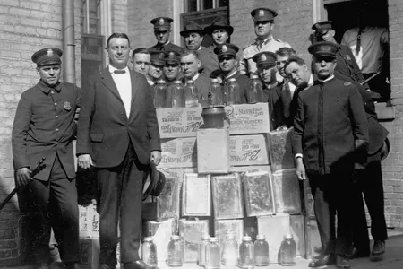 Police officers stand proudly with jars and crates of moonshine, brewed illegally duirng the prohibition. Washington, D.C.