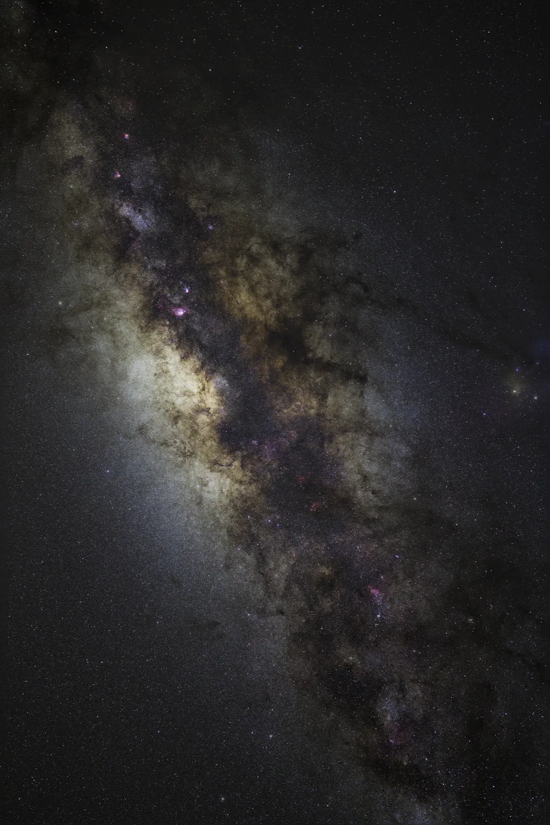 the stars and web-like structures of the Milky Way glow in a belt stretching diagonally from the image's top left to bottom right