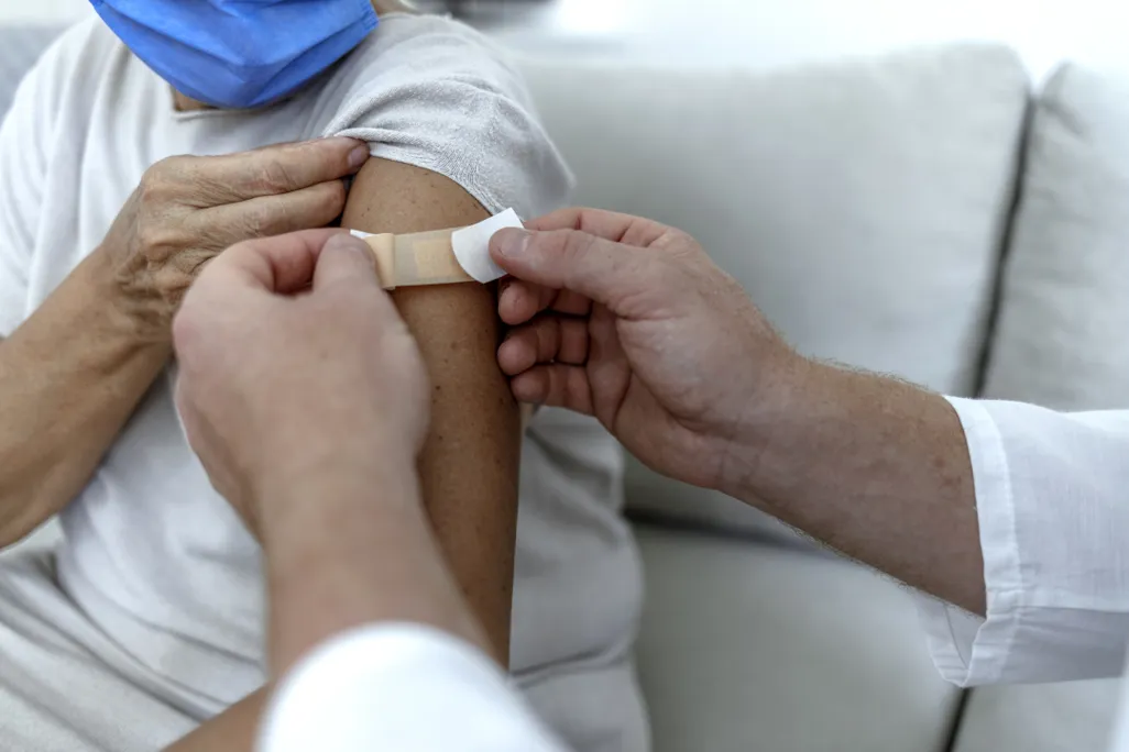 person getting bandaid over vaccine