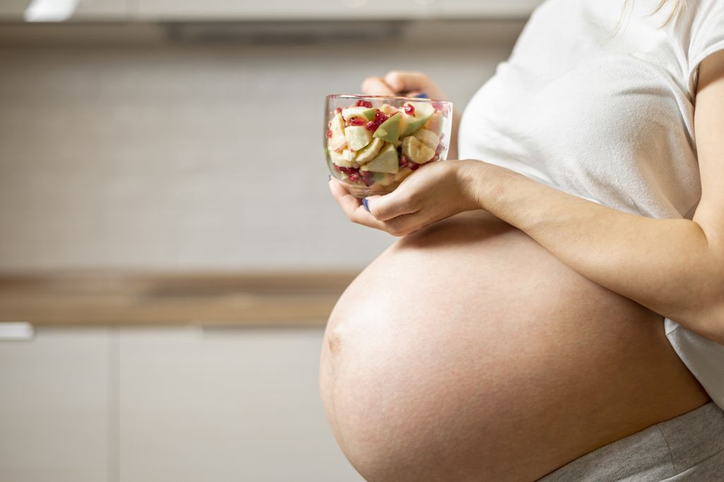 Very pregnant woman holding a bowl of food