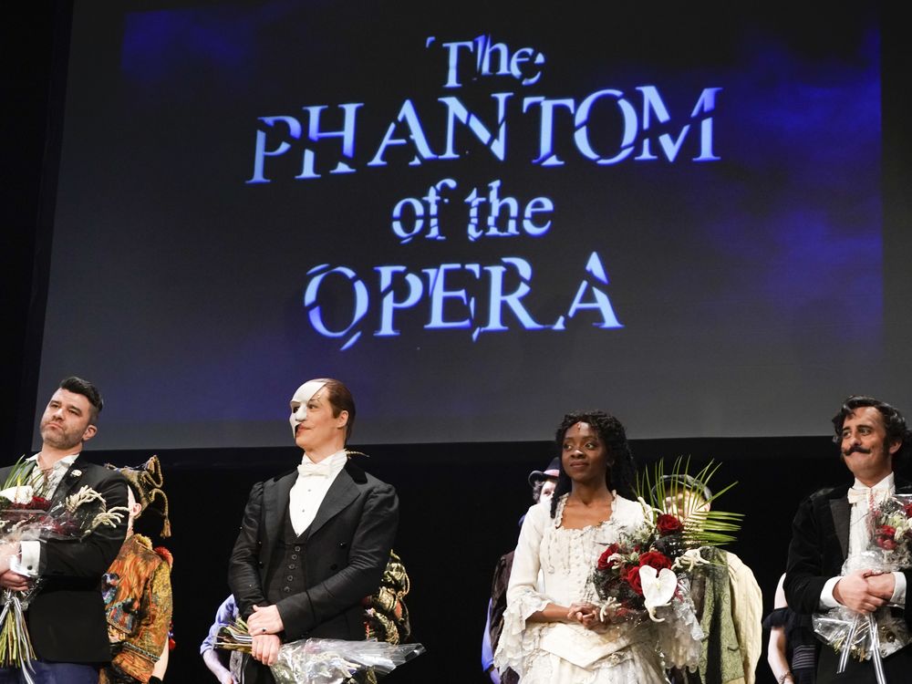 Four cast members of the final production of "The Phantom of the Opera" on Broadway stand on stage holding flowers