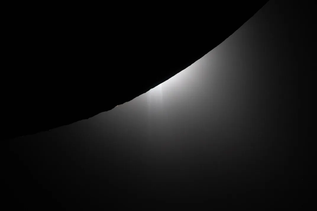 the sun sets behind the moon, lighting up mountains along its outer limb