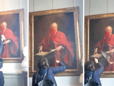 A video posted on social media shows a woman spraying red paint on the portrait, then cutting it with a handheld tool.