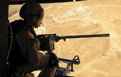 From A UH-1N Huey helicopter, Corporal Andy Vistrand, a "Gunrunner" in Light Attack Helicopter Squadron 269, scans the countryside of Anbar province from behind a .50-caliber machine gun.