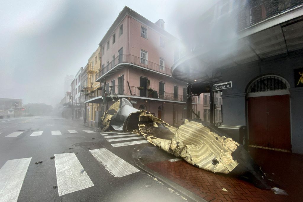 A view partially obscured by rain of a historic building at an intersection, with a part of a roof or building obstructing the entire road